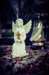 beautiful cute innocent white angel during All Saints Day in the cemetery