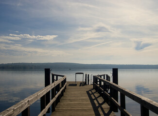 Naklejka premium Lake and wooden pear. Water landscape with blue sky and clouds. Travel, outdoor and vacation view. Schwielowsee am Potsdam (Germany)