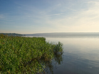 Fototapeta premium Lake and wooden pear. Water landscape with blue sky and clouds. Travel, outdoor and vacation view. Schwielowsee am Potsdam (Germany)