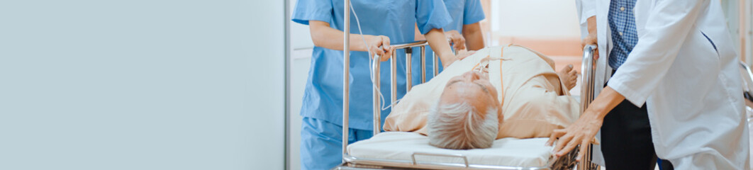 Group of Asian emergency doctor and nurse team push emergency stretcher, transport senior patient in hospital. Health care paramedic service or medical rescue operation concept. Banner with copy space © Urbanscape