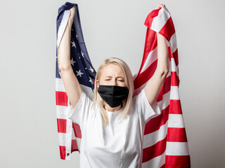 Blonde girl in face mask with USA flag on white background