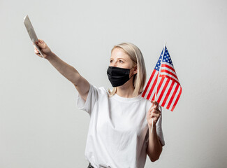 Blonde girl in face mask with USA flag and money on white background