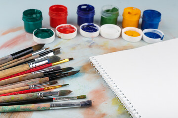sketchbook, paint brushes and paints top view with copy space