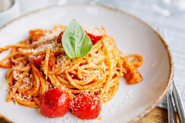 Spaghetti with tomatoes in a plate on the table. Traditional Italian cuisine. Close-up.