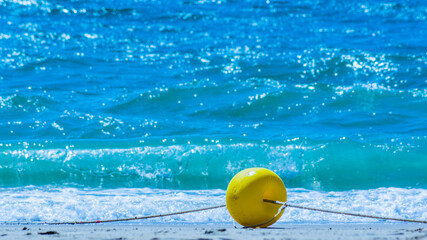Yellow buoy on a sandy beach on a rope