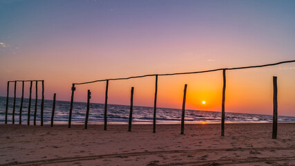 wooden poles on the beach at sunset glow
