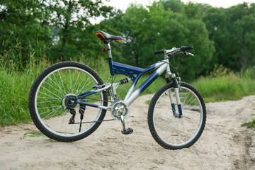 Fototapeta na wymiar blue mountain bike on sandy road on forest background