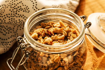 Homemade granola with nuts and seeds in glass jar on a wooden background for healthy breakfast....