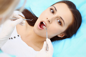 Young female patient visiting dentist office.Beautiful woman feeling fear and pain during doctor working at teeth. Dental clinic, stomatology concept