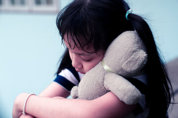 Asian sad child girl hugging teddy bear with love