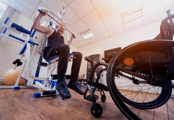 Obraz premium Disabled man doing strength exercises separate from the wheelchair.