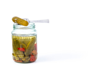daylight. pickled cucumbers on a white plate in a glass jar. At the very top, one is pinned onto a fork.