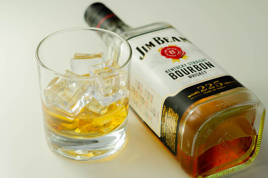 LONDON, UNITED KINGDOM - AUGUST 04, 2020 Glass of Jim Beam kentucky straight bourbon whiskey with ice cubes and a typical square bottle