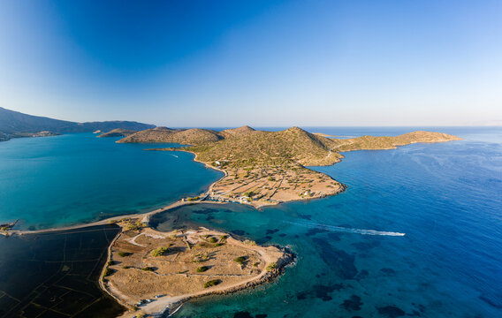 Aerial view of the crystal clear ocean and dry summer coastline of Kolokitha and Olous near Elounda, Crete, Greece