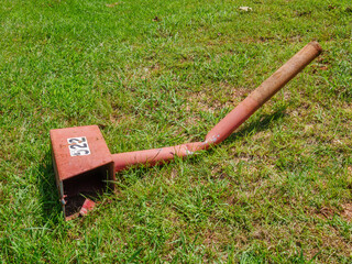 old red mailbox lying in grass after being struck by a car