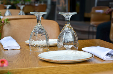 Table on the veranda of the restaurant, served for two: two inverted glasses, napkins and cutlery...