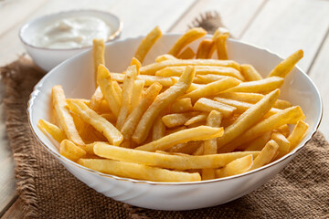 Hot golden french fries with sauce on wooden background. Homemade rustic food.