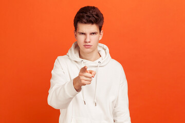 Confident young man with stylish hairdo in casual hoodie pointing finger on you and looking...