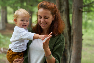 mom holding a small child walking in the park