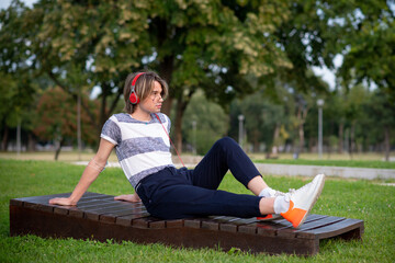 Young gay man listening music in a park