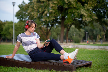 Young gay man listening music in a park
