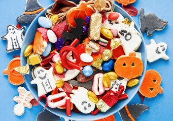 Halloween Jack o Lantern candy bowl with candy and halloween cookies Trick or Treat on blue background