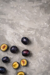 Fresh ripe plum fruits whole and sliced on stone concrete background, top view copy space