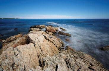 Rocks and slow motion ocean wave at Rye Harbor State Park, Portsmouth NH, USA. The park affords scenic views of the Atlantic Ocean, the Isles of Shoals, and Rye Harbor, also called Ragged Neck.