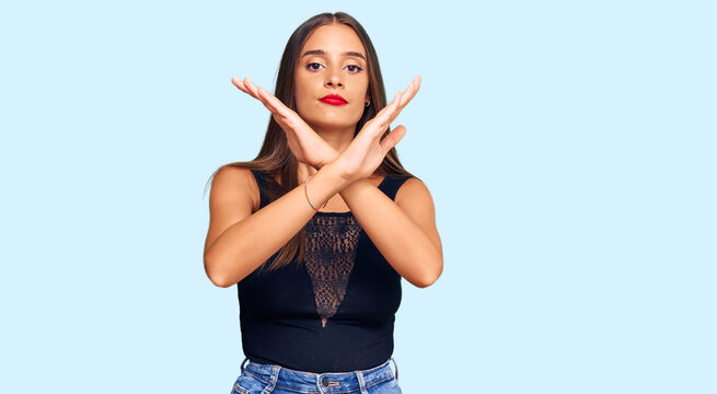 Young hispanic woman wearing casual clothes rejection expression crossing arms doing negative sign, angry face