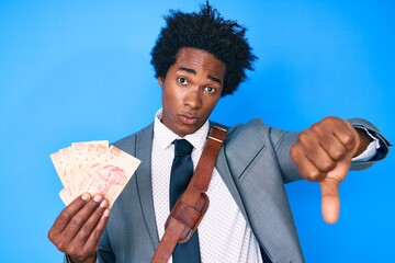 Handsome african american man with afro hair holding mexican pesos with angry face, negative sign showing dislike with thumbs down, rejection concept