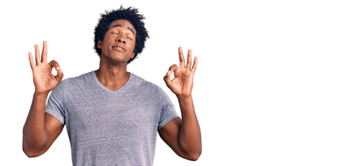 Handsome african american man with afro hair wearing casual clothes relax and smiling with eyes closed doing meditation gesture with fingers. yoga concept.