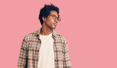 Handsome african american man with afro hair wearing casual clothes and glasses smiling looking to the side and staring away thinking.
