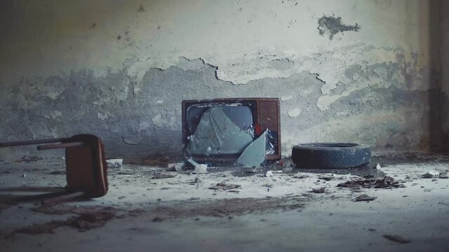 Throwing a rock to an abandoned television, broken screen in old television. Slow motion