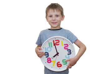 A preschool boy stands against a light background with a large clock in his hands showing 8 o'clock. The photo is horizontal, the child looks at the camera. Concept - Everything is in our hands.