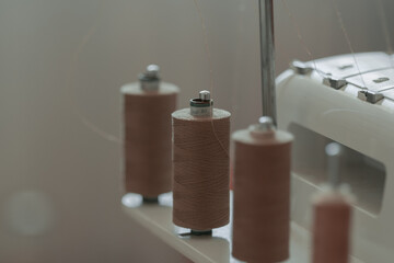 Light brown sewing thread on sewing machine. Neutral colors. designer space