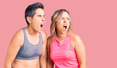 Fototapeta na wymiar Couple of women wearing sportswear angry and mad screaming frustrated and furious, shouting with anger. rage and aggressive concept.