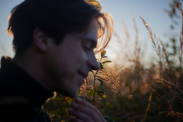 Young man in the morning light. Portrait of a guy walking in nature. Rest in the forest. The man is...