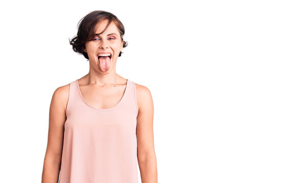 Beautiful young woman with short hair wearing casual style with sleeveless shirt sticking tongue out happy with funny expression. emotion concept.
