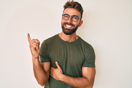 Young hispanic man wearing casual clothes and glasses smiling happy pointing with hand and finger to the side