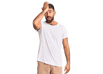 Young hispanic man wearing casual white tshirt surprised with hand on head for mistake, remember error. forgot, bad memory concept.
