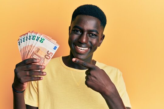 Young african american man holding 50 euro banknotes smiling happy pointing with hand and finger