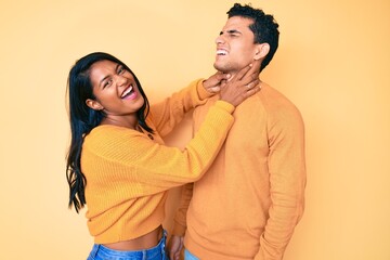 Beautiful latin young couple wearing casual clothes together shouting suffocate because painful strangle. health problem. asphyxiate and suicide concept.