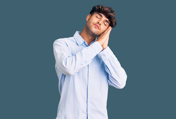 Young hispanic man wearing casual shirt sleeping tired dreaming and posing with hands together while smiling with closed eyes.