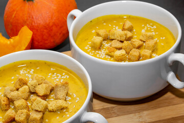 Autumn pumpkin soup with sesame seeds on a wooden background