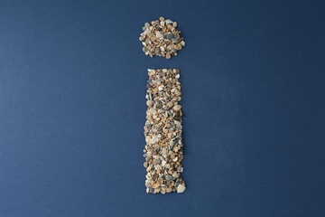 The letter I is lined with small pebbles on a blue background