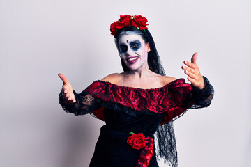 Young woman wearing mexican day of the dead makeup smiling cheerful offering hands giving assistance and acceptance.