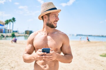 Fototapeta na wymiar Handsome fitness caucasian man at the beach on a sunny day wearing summer hat