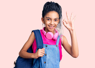 Cute african american girl holding student backpack using backpack doing ok sign with fingers, smiling friendly gesturing excellent symbol