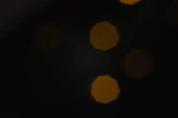 Abstract glitter bokeh on black background. Image with selective focus, noise effect and toning