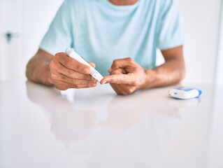 Young hispanic diabetic man measuring glucose level at home